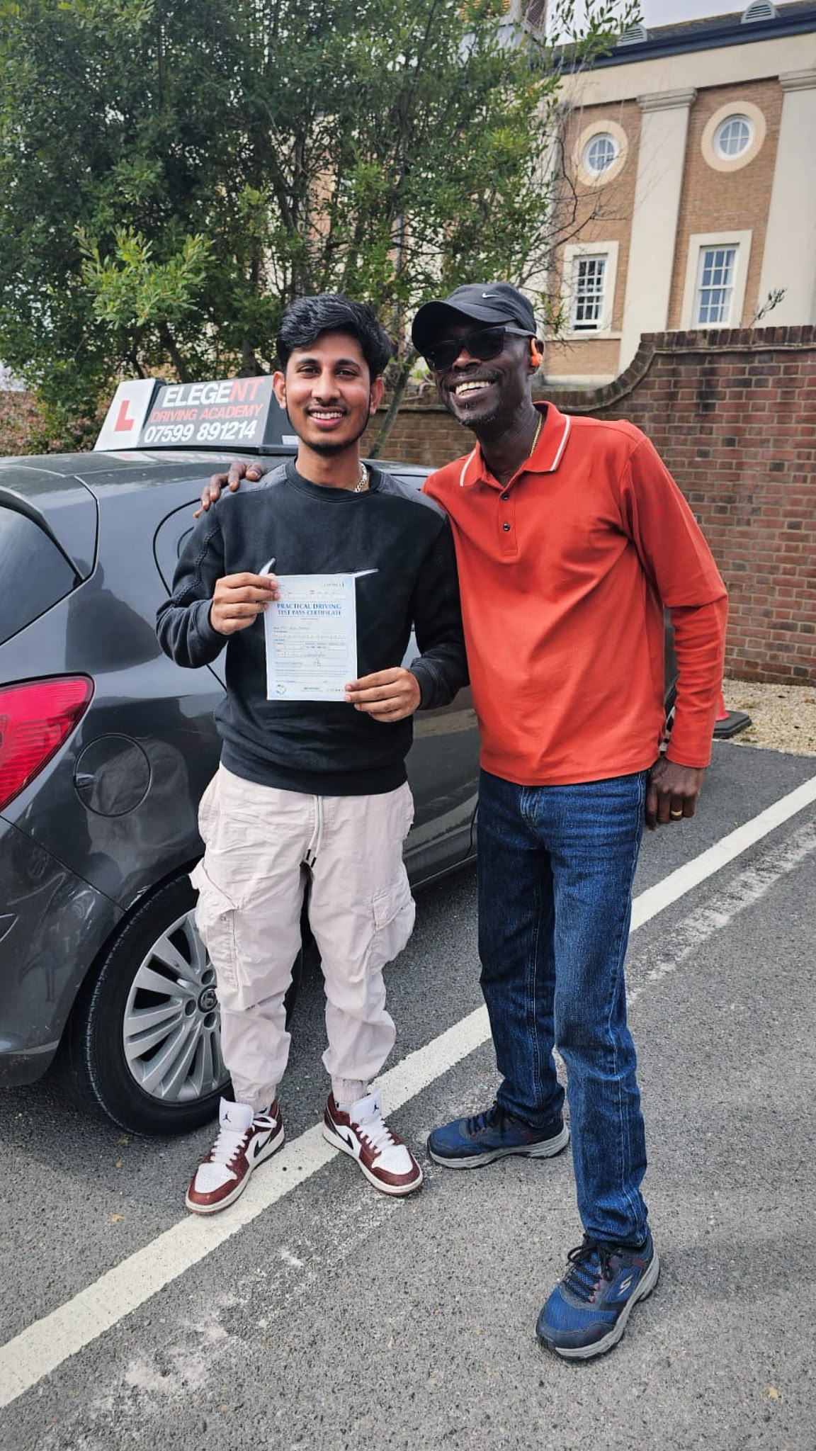 Learner driver proudly holding test pass certificate with instructor